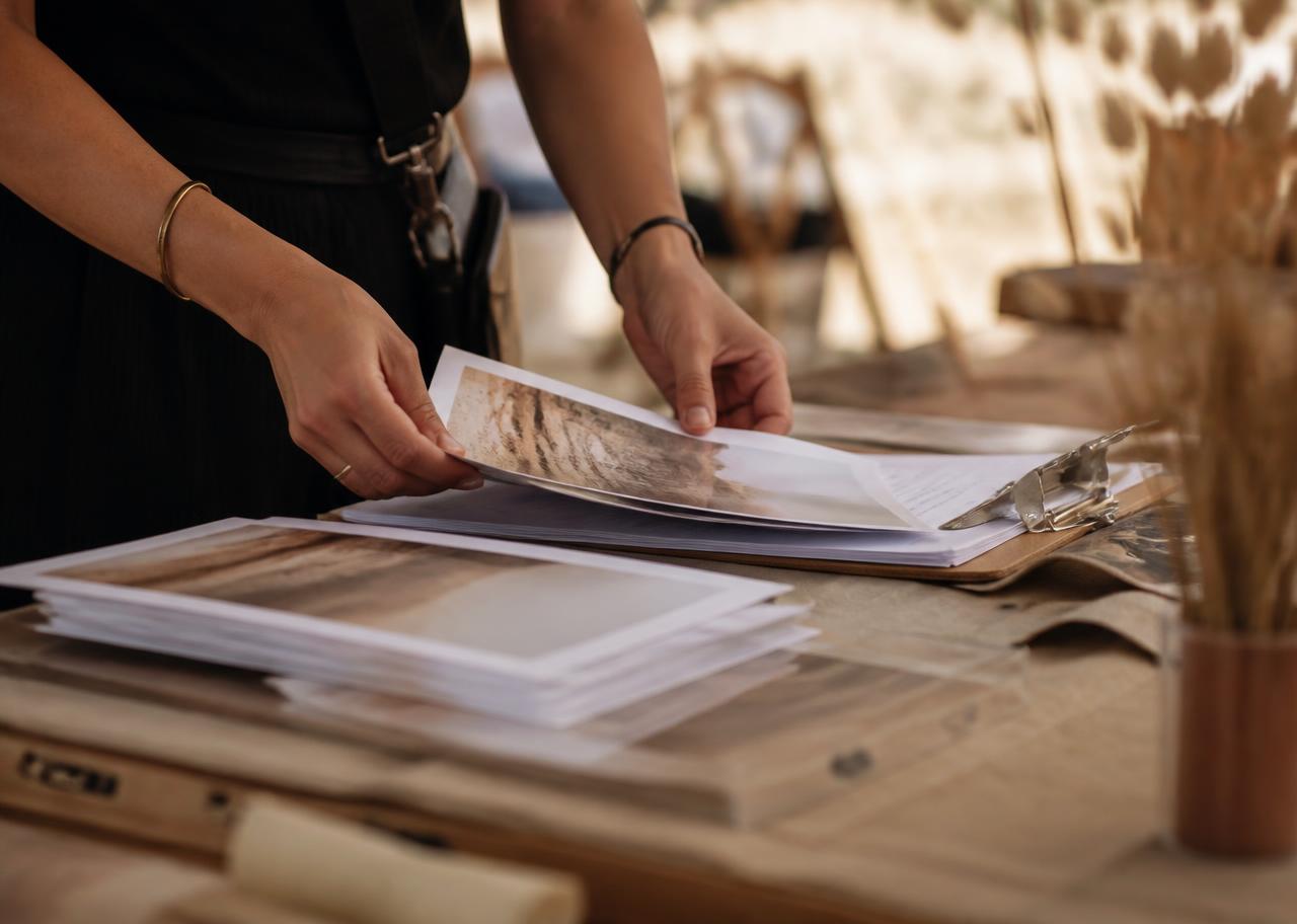 Close-up of hands organizing printed campaign materials on a table before an event